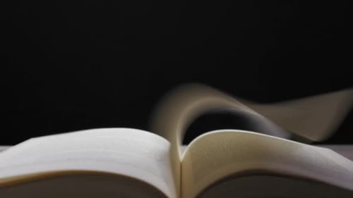 Pages Flipping in a Book Against Black Background