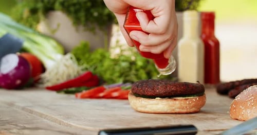 Assembling Tasty Burger with Fresh Veggies and Sauce