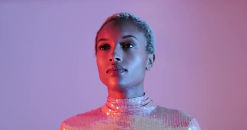 High Fashion model woman in colourful bright lights looking to camera in studio