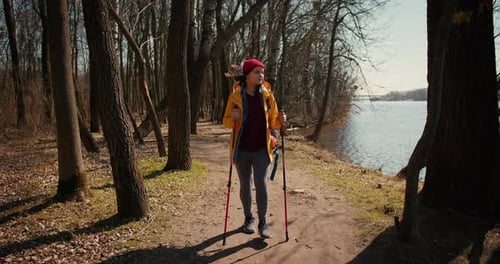 Backpacker Hiker Girl with Hiking Poles Walking Between Trees in a Mountain Forest Hispanic Teenager