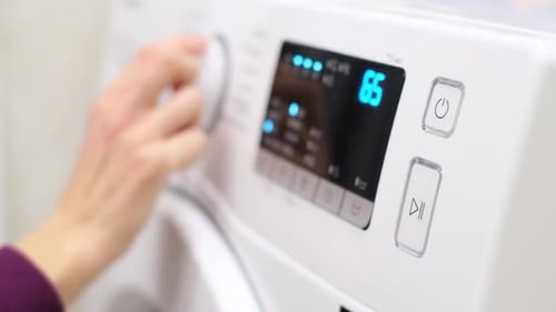 Closeup of a Woman's Hand Turning on the Washing Machine