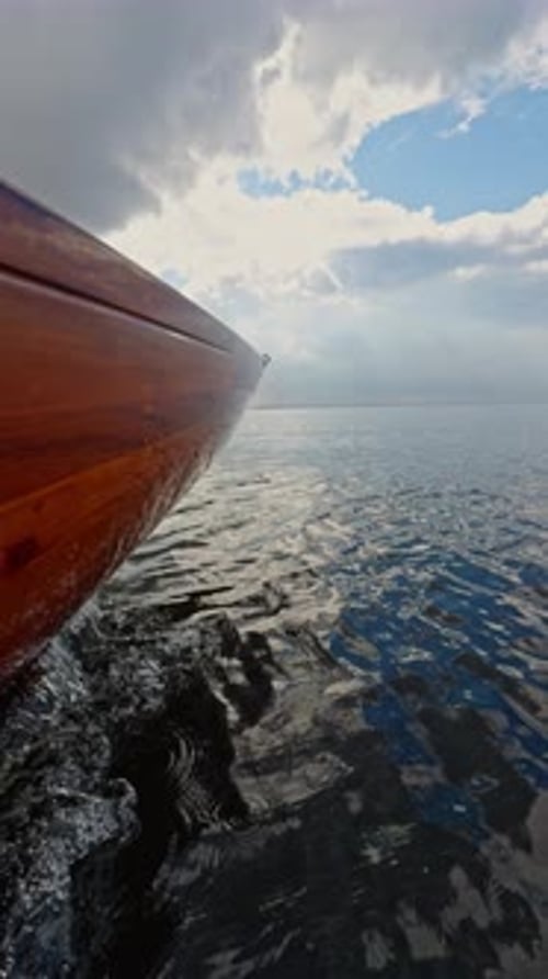 Boat prow floats on water under cloudy sky