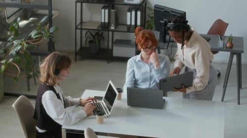 Girl Coming up to Colleague with Laptop and Asking for Help in Call Centre