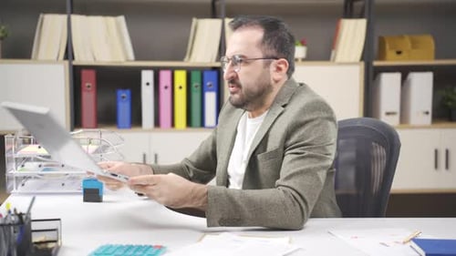 Frustrated Man Slams Laptop Shut at Office Desk