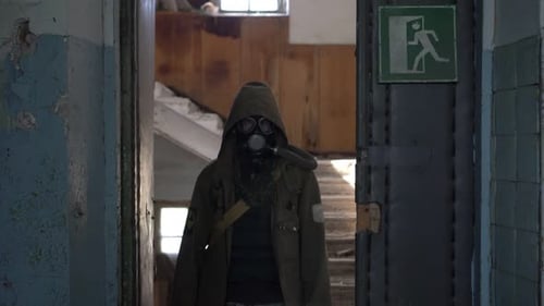 Ein Survivalist Stalker in einer Gasmaske betritt die Tür eines zerstörten verlassenen Gebäudes