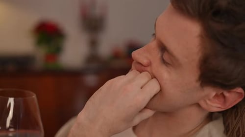 Side View Closeup of Young Thoughtful Man Drinking Red Wine Looking Away Sitting in Rocking Chair