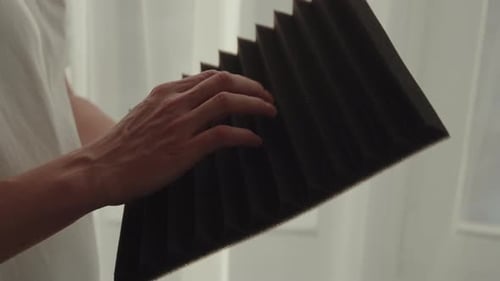 Man Examining Texture of Acoustic Foam Panel Considering Soundproofing Solutions for Modern Office
