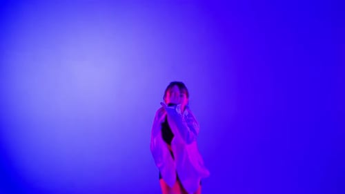 Young Woman Wearing a Top Shorts and a Shirt Performing Contemporary Dance in Studio Neon Blue Pink