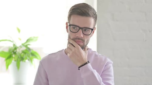 Young Adult Man Thinking and Touching Face