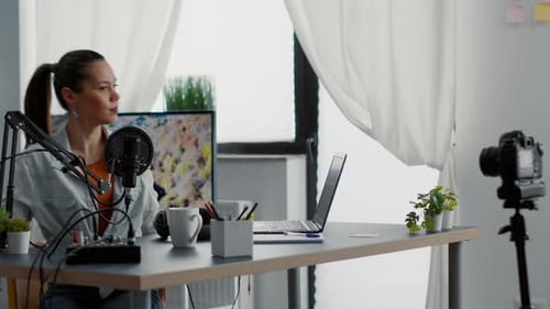 Attractive Vlogger Sitting at Studio Desk While Starting Recording Video