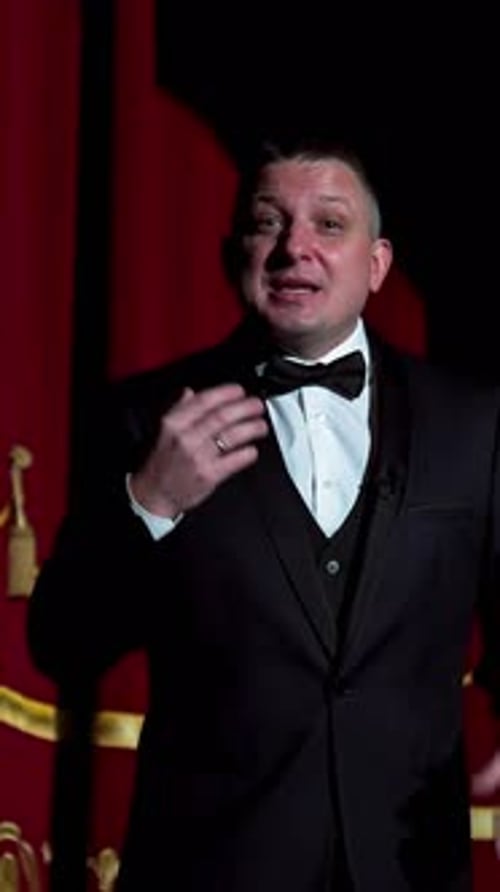 Actor on a stage. Adult man talks to the public in microphone or sings songs. Theater concept.