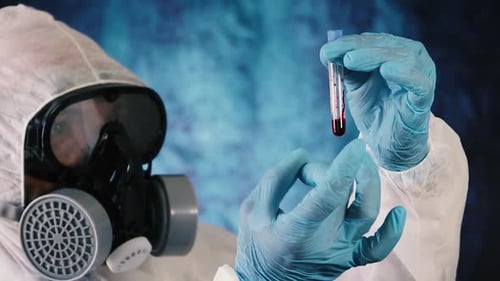 Covid-19 biologist holding and tapping blood sample test tube. Blue background