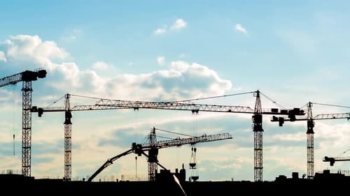 Silhouettes of Construction Cranes Building a House in the Evening