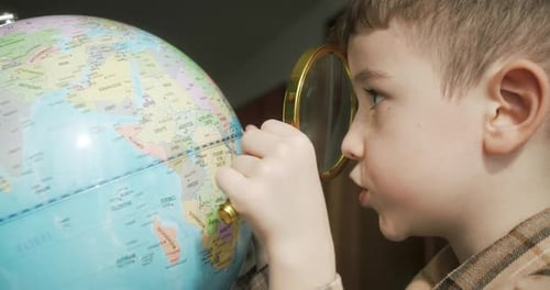 Boy Studies Globe with Magnifying Glass