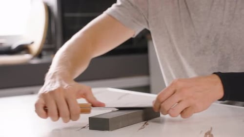 Close Up of Hands Sharpening Knife on Whetstone with Focus on Technique, Precision Tool Care Concept