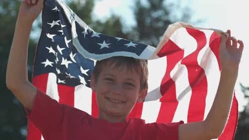 Smiling Boy Holding American Flag Outdoors in Sunlight