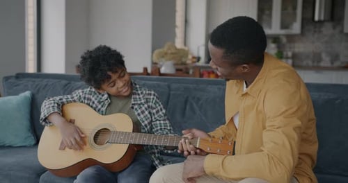 Boy Learns Guitar From Adult at Home