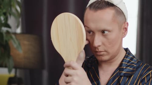 Adult Applies Makeup Looking in Mirror