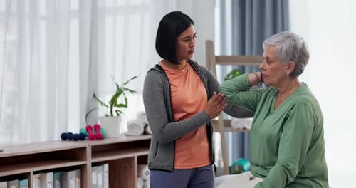 Young Adult Supporting Senior Woman With Arm Exercise