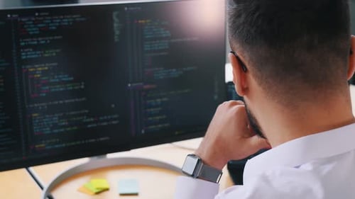 Business man programmer is sitting by computer in office and working.