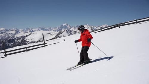 Skier in the red jacket skiing down the slope in the winter
