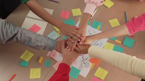 Teamwork Hands Stacked over Mind Map and Sticky Notes