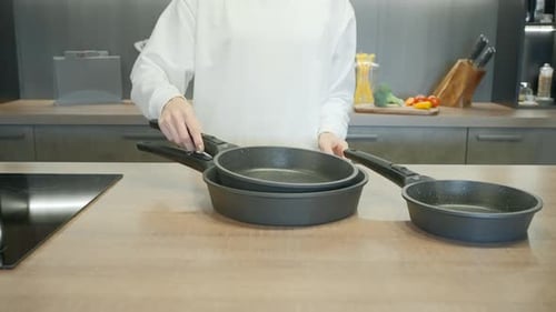 New Set of Frying Pans Demonstrated By a Chef in White Uniform