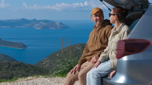 Couple Enjoying Scenic View From Car Trunk