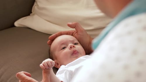 Adorable Baby Lying on Couch, Interacting with Parent