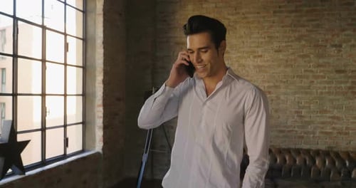 Smiling Young Adult Man Talking on Cellphone Indoors