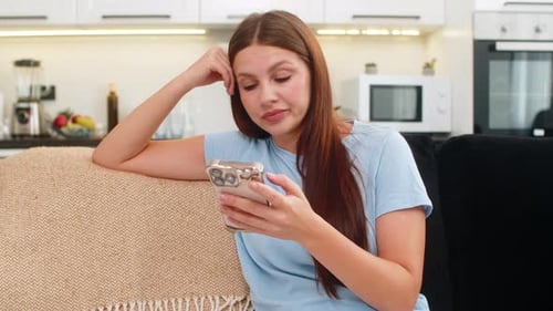 Woman with smartphone relaxing on sofa at home