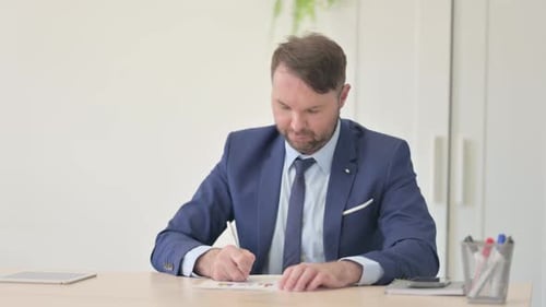 Man Analyzing Financial Charts at Office Desk
