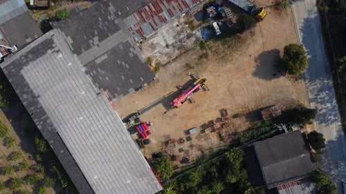 Mobile crane stands waiting to lift steel at a warehouse.