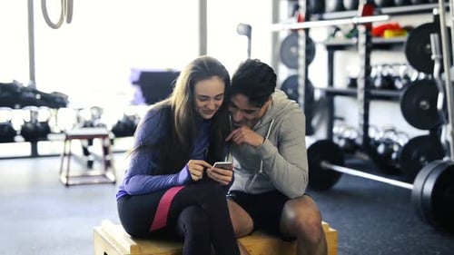 Fit Couple in Modern Crossfit Gym with Smartphone