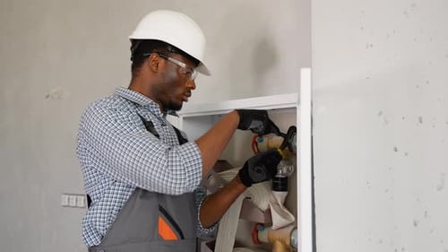 African Plumber Installs or Inspects Fire Hydrant in Office