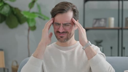 Man Massaging Temples due to Headache Indoors