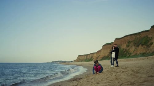Family vacation on ocean beach in nature with happy parents and child playing