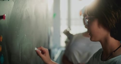 Elementary School Boy Solving Mathematical Problems Writing on the Chalkboard
