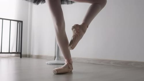 Ballerina's feet in pointe shoes practicing ballet in studio