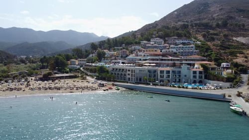Drone flying over the sea overlooking a beach next to a resort in Greece Crete with many houses on a