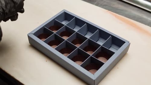 Chocolatier Assembling Delicious Treats into a Box