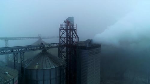 Approaching the high building at elevator plant emitting thick white smoke. Aerial viewя