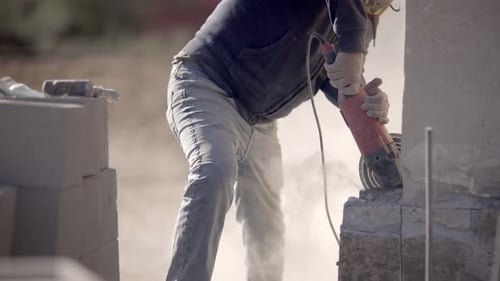 Construction worker cuts concrete with angle grinder, slow mo