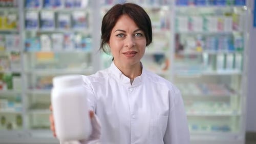 Woman Holding Medicine Container in Pharmacy Close Up