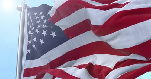 Waving American Flag on Flagpole in Sunny Sky