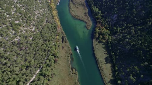 Aerial view of winding river with boat and lush forest, Croatia.