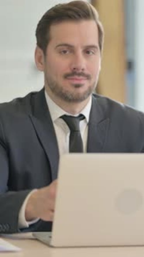 Businessman Works on Laptop and Gives a Thumbs Up