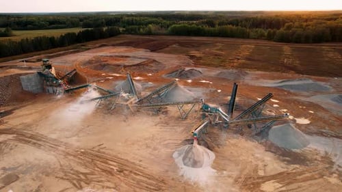Industrieller Steinbruch bei Sonnenuntergang mit Maschinen und weitläufiger Bergbaulandschaft