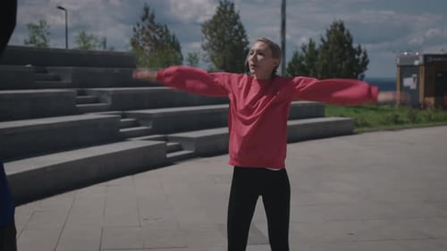 A Man and a Woman Do Warmup Exercises on the Street Summer Day in the City Park The Couple is