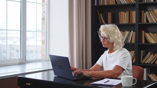 Senior Woman Typing on Laptop at Home Office